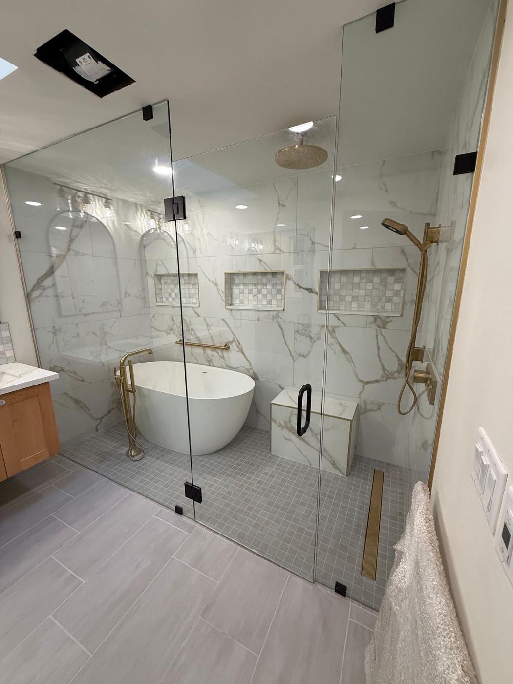 Frameless enclosure in calacatta marble with brushed gold fixtures