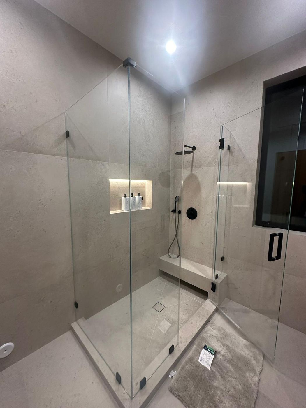 Corner frameless shower enclosure with built-in bench