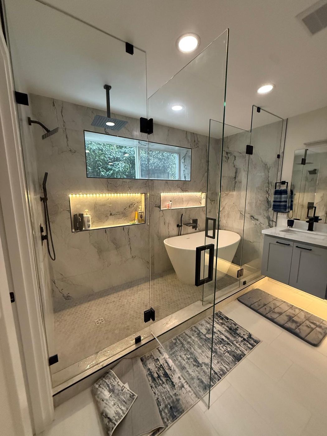 Frameless shower enclosure with lit marble niche
